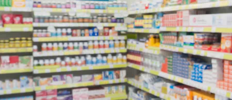 Pharmacy shelves filled with prescription pill bottles, representing commonly abused opioids, stimulants, and sedatives.