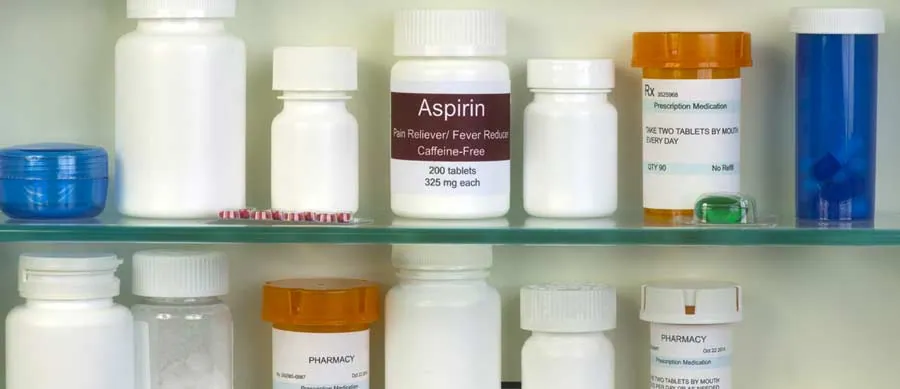 Several prescription medication bottles and pill containers on a shelf, representing unused and expired drugs awaiting safe disposal.