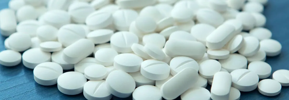 White antidiarrheal pill tablets spilling from a bottle, representing high‑dose loperamide misuse for opioid effects.
