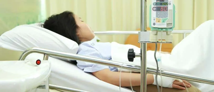 A patient lying reclined in a hospital bed with monitoring equipment—visually representing the risk and medical setting associated with rapid detox.