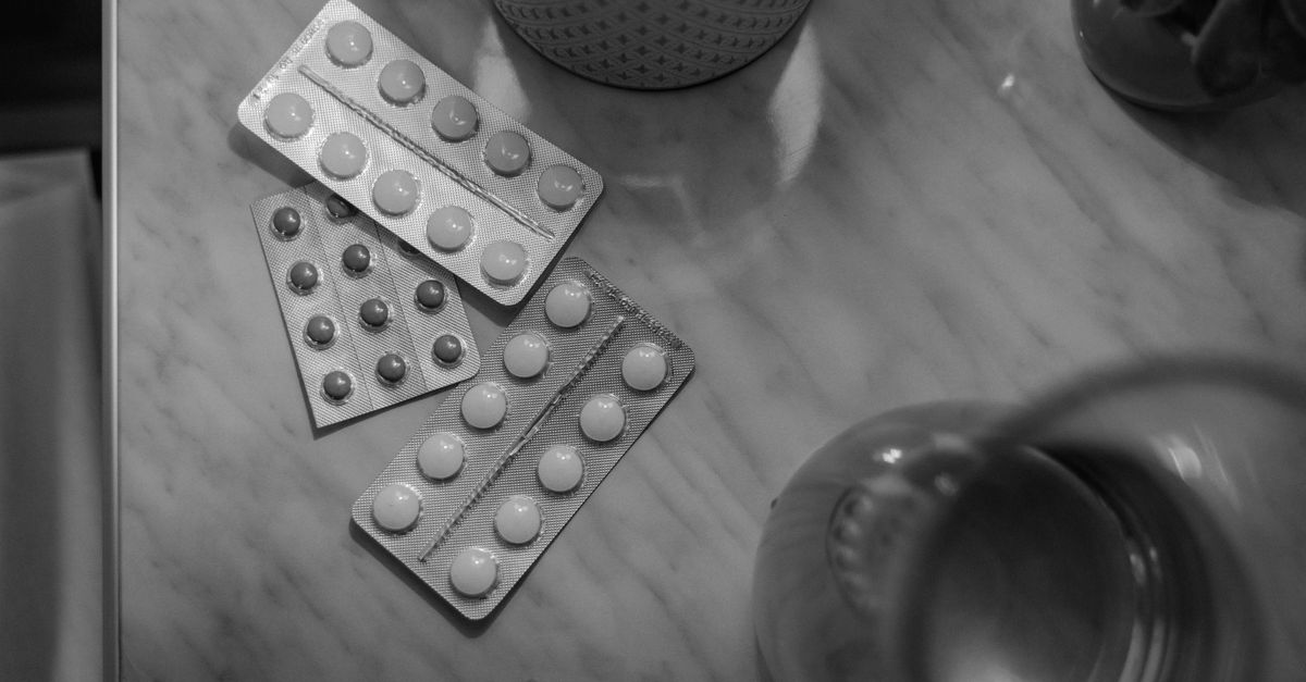 Monochrome image showing medication blisters on a table with soft lighting.